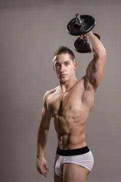 Young man bodybuilder arm raised outstretched dumbbell Stock Photos