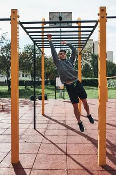 Young man bodybuilder exercising on monkey bars during his workout in a moder Foto stock