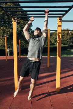 Young man bodybuilder exercising on monkey bars during his workout in a moder Stock Photos