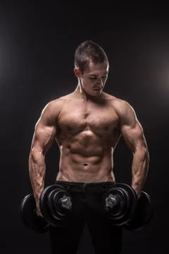 Young man bodybuilder looking sideways holding dumbbells Stock Photos