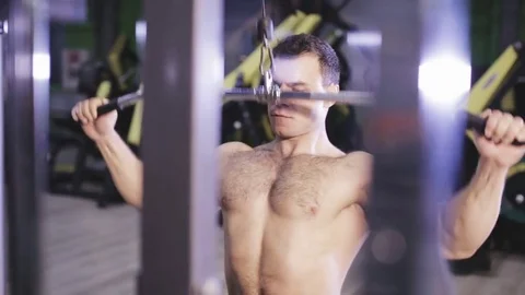 Young Man Bodybuilder Is Working On His back muscles With lat Machine Stock Footage 81055336
