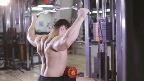 Young Man Bodybuilder Is Working On His back muscles With lat Machine Stock Footage 81055560