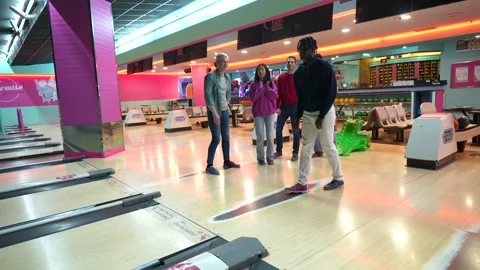 Young man bowling with friends cheering in bowling alley Stock Footage 308262210