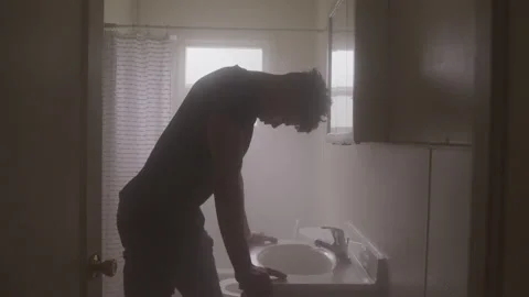 Young Man Bows Head Over Bathroom Sink Vidéo 208711333
