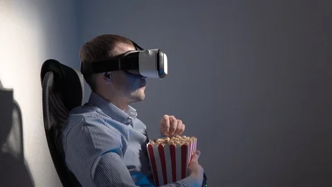A young man with a box of popcorn in his hand watching a video in a virtual Stock Footage 101847823
