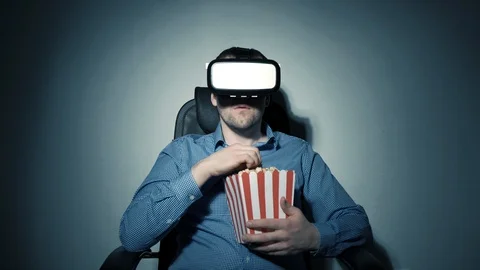 A young man with a box of popcorn in his hand watching a video using a virtual Stock Footage 102914771