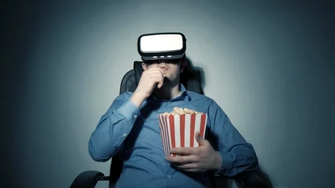 A young man with a box of popcorn in his hand watching a video using a virtual Stock Footage 102915073