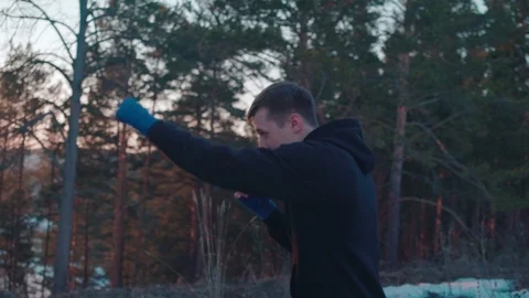 Young man boxing in slowmotion in evening forest Stock Footage 106509946