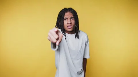 Young man with braids is pointing at the camera with an intense expression .. Stock Footage 313280141