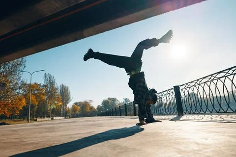 Young man break dancer dancing on urban background performing acrobatic stunts Stock Photos