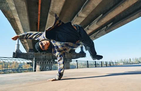 Young man break dancer dancing on urban background performing acrobatic stunts Stock-Fotos