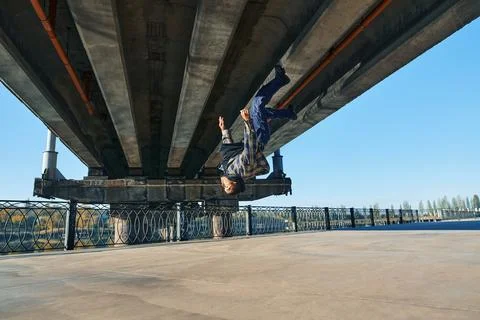 Young man break dancer doing somersault acrobatic stunts dancing on urban Stock Photos