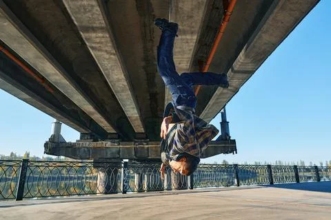 Young man break dancer doing somersault acrobatic stunts dancing on urban Foto stock