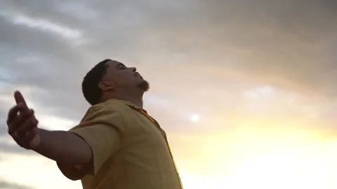 Young man breathing deeply at sunset with open arms Stock Footage 313739888