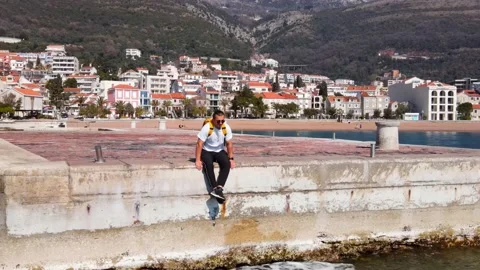 Young man with bright backpack on his back sat down to relax on pier after long Stock Footage 158839927