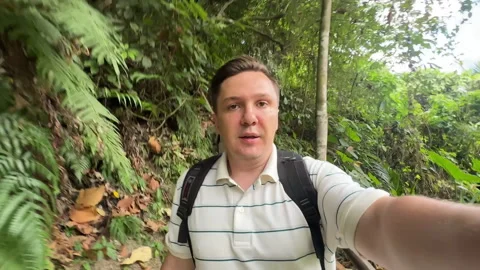 Young man broadcasts walking through wild rainforest on vacation Stock Footage 307485477