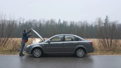 A young man a broken car and opens the hood.  Stock Footage 144673647