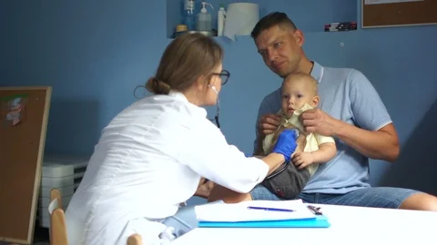 Young man brought his one and a half year old son to a doctor for examination by Stock Footage 117897976