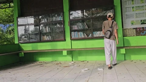 Young Man Browsing Books at Telaga Buret Nature Library Tulungagung Stock-Footage 332969700
