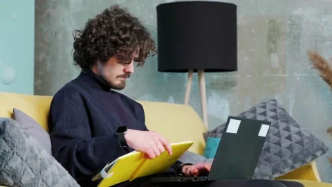 Young man is browsing at his laptop and writing notice on his paper notebook. Stock Footage 151664579