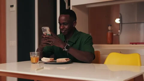 Young Man Browsing Phone at Kitchen Table Stock Footage 310016136