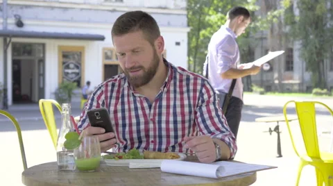 Young man browsing smartphone, during lunch. 库存影片 67603973