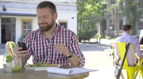 Young man browsing smartphone, during lunch, slider shot, right. 库存影片 67604058