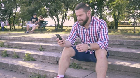 Young man browsing smartphone, sitting on stairs. Vídeos de archivo 67239655
