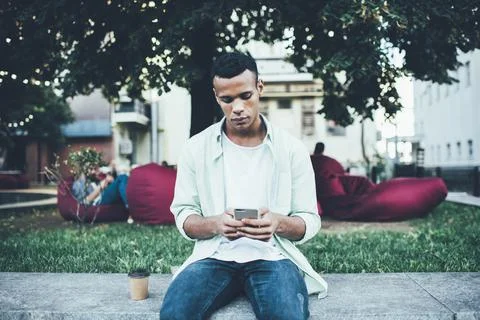 Young man browsing smartphone while resting in park Stock Photos