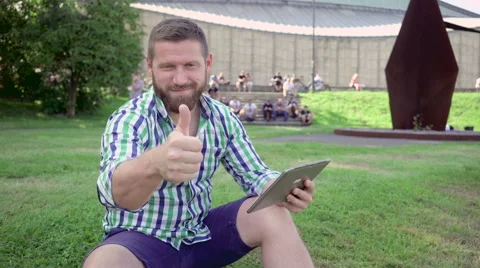Young man browsing tablet shows ok for camera. Steadicam. Vídeos de archivo 67236562