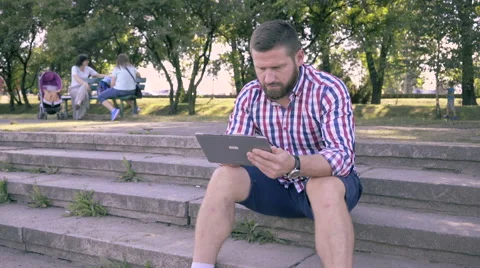 Young man browsing tablet, sitting on stairs. 库存影片 67241846