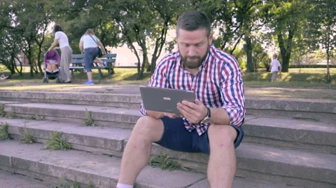 Young man browsing tablet, sitting on stairs. Slider shot. 库存影片 67242045