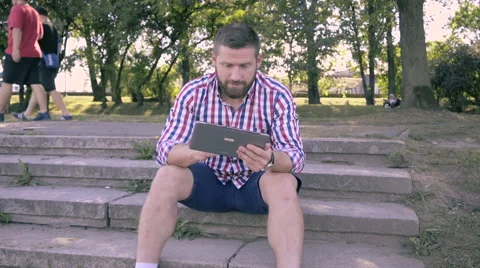 Young man browsing tablet, sitting on stairs. Slider and pan shot. 库存影片 67242238