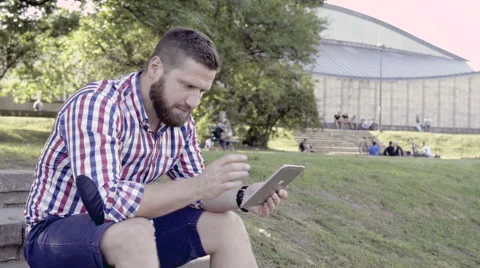 Young man browsing tablet, sitting on stairs. Slider shot. 库存影片 67247547
