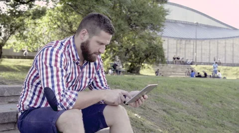 Young man browsing tablet, sitting on stairs. Slider shot. 库存影片 67247702