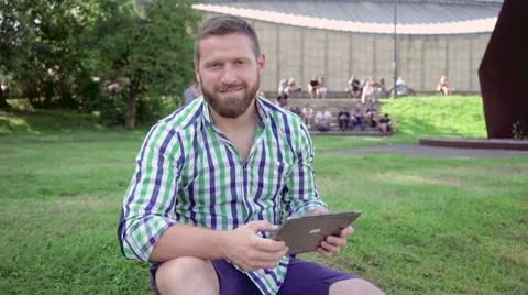 Young man browsing tablet smiles for camera. Steadicam. 库存影片 67236325