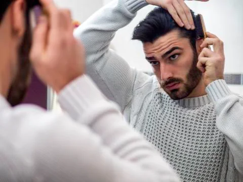 Young Man Brushing and Combing Hair in Mirror Stock Photos