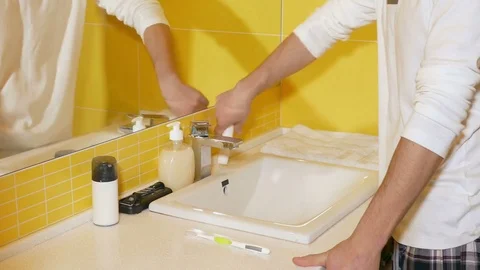 Young man brushing his teeth in the bathroom Stock Footage 71778679