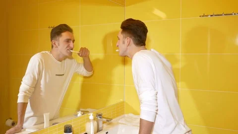 Young man brushing his teeth in the morning Video stock 71778756