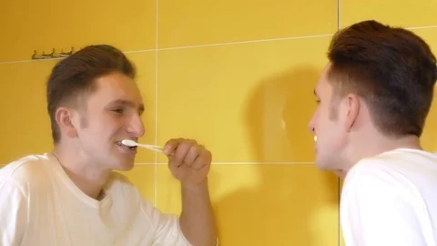 Young man brushing his teeth in front of the mirror Stock Footage 71778966