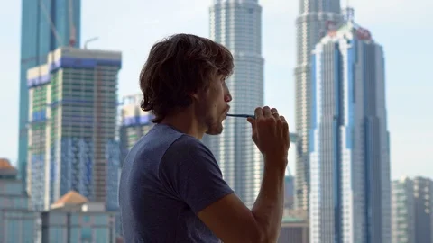 Young man brushing his teeth standing on a balcony Stock Footage 93528708