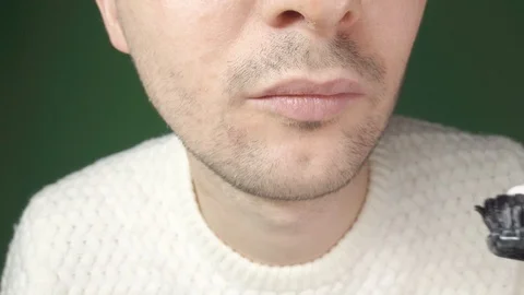 Young man brushing his teeth with a black toothbrush, close-up on a green Stock Footage 124361788