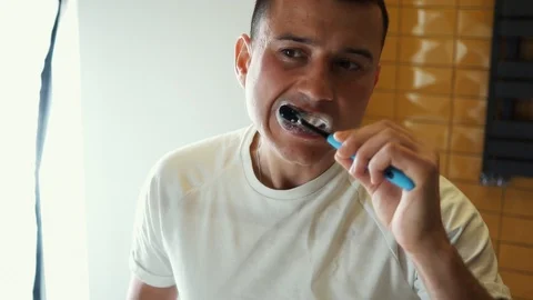 Young Man Brushing Teeth In Bathroom in front of mirror. Doing hygiene routine Video stock 121003199