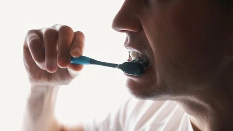 Young Man Brushing Teeth In Bathroom in front of mirror. Doing hygiene routine Stock Footage 121003264