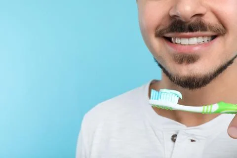 Young man brushing teeth on color background, closeup. Space for text Stock Photos
