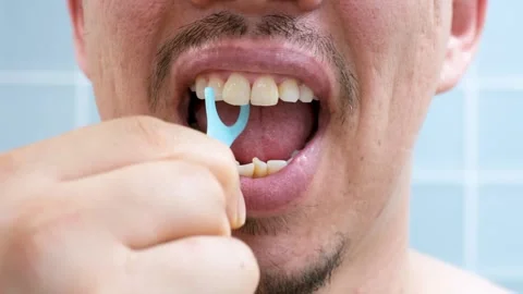 Young man brushing teeth with disposable dental floss close-up against the Stock Footage 311041635