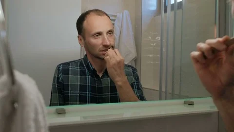 Young man brushing teeth while standing in bathroom indoors. Stock Footage 79809463