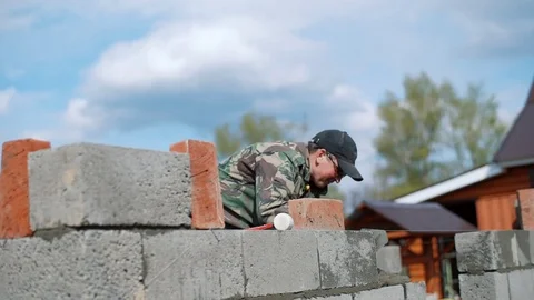 A young man-builder puts a solution for bricks Stock Footage 79787764