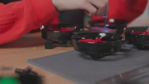 Young man building quadcopter from kit. Close-up shot of young male hands in red 動画素材 186140425