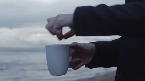 Young man with burning cup in hand standing on coast storm clouds on background Stock Footage 74363965